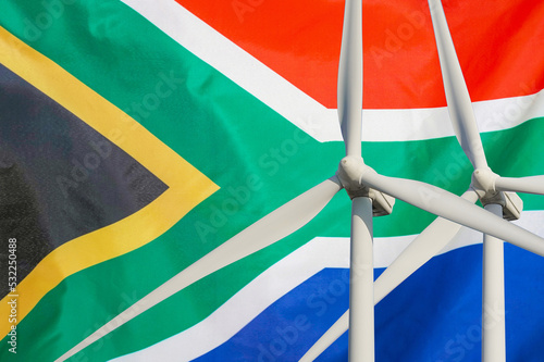 Two Wind Turbines for alternative energy on South Africa flag background. Energy development and energy crisis. Eco power and Wind stations for renewable electric energy production in South Africa