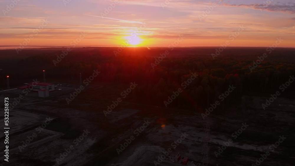 Fototapeta premium Bright sunset over the horizon in the tundra where oil and gas are extracted. A drone view of the sunrise in Siberia. Sunset over the extraction of fossil fuels in the global economy. Oil production.
