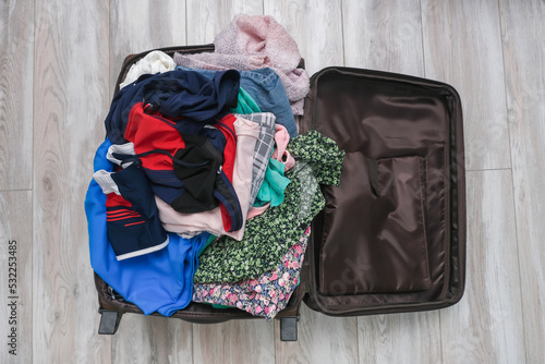 Obraz na plátně Open suitcase on the floor with a messy pile of clothes, getting away from home