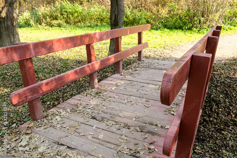Small wooden brodge with red railings in a park in sunny day Small wooden brodge with red railings in a park in sunny day