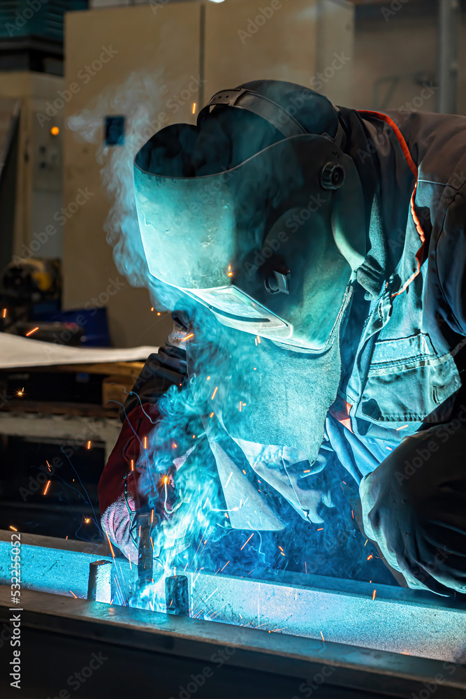 Obraz na plátně A welder welds long beams with a gas welding machine at an industrial plant