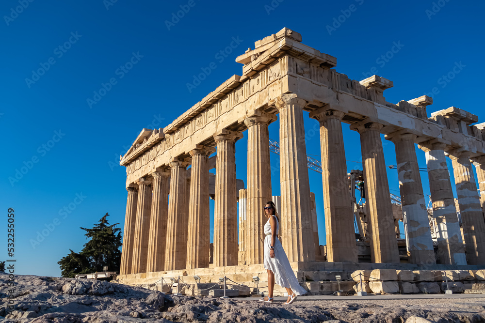 Rear view of tourist woman in white dress looking at Parthenon of Acropolis of Athens, Attica, Greece, Europe. Ruins of ancient temple, the birthplace of democracy. Girl wearing golden laurel crown Rear view of tourist woman in white dress looking at Parthenon of Acropolis of Athens, Attica, Greece, Europe. Ruins of ancient temple, the birthplace of democracy. Girl wearing golden laurel crown
