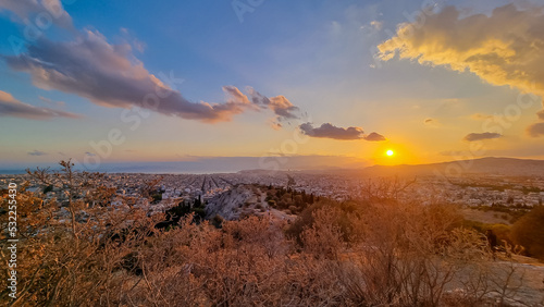 Panoramic view during sunset of the city of Athens seen from Filopappou Hill (hill of muses), Athens, Attica, Greece, Europe. Athens cityscape and Aegean sea. Beautiful sunset point with aerial view