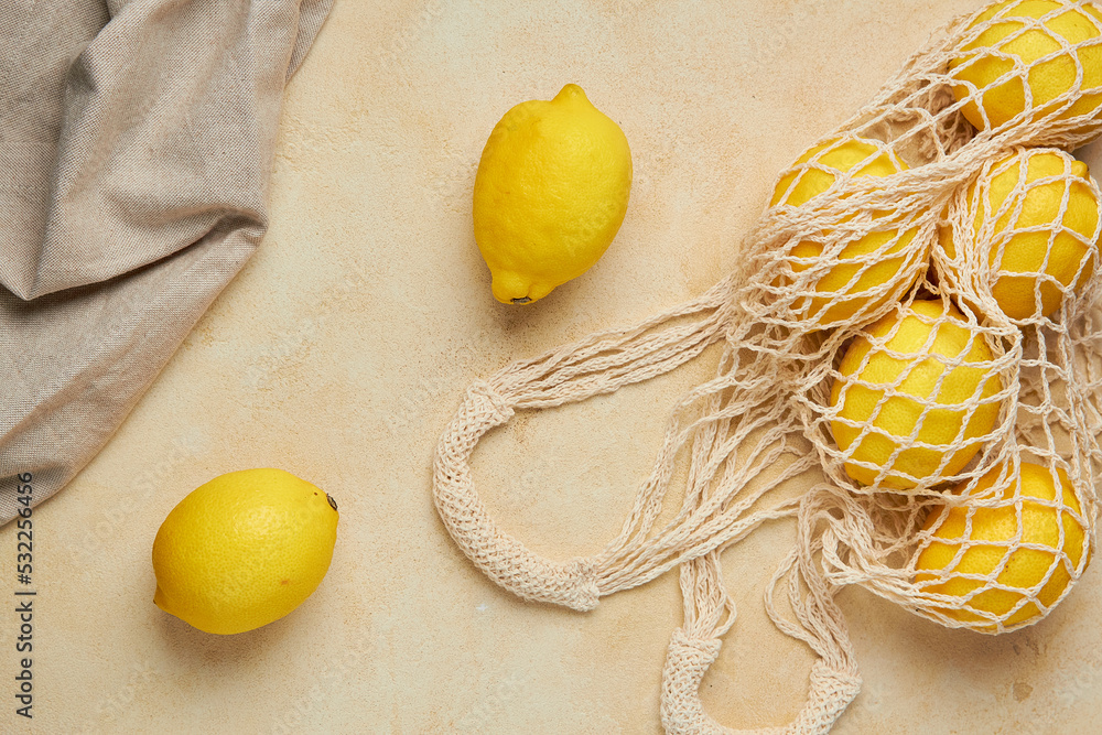 Fresh citrus in mesh bag on beige background. Lemons and limes in
