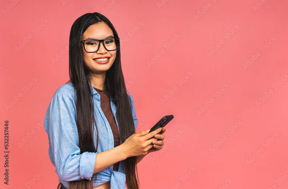 Happy Asian portrait beautiful cute young woman teen smiling excited typing text message on smart mobile phone enjoys online communication isolated on pink background with copy space. Happy Asian portrait beautiful cute young woman teen smiling excited typing text message on smart mobile phone enjoys online communication isolated on pink background with copy space.