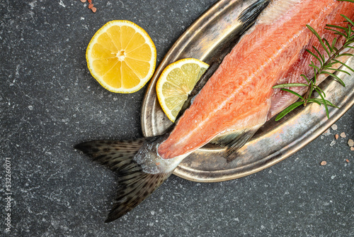 Fresh raw salmon red fish, Raw fish trout steak with spices and herbs on dark slate table. place for text, top view photo