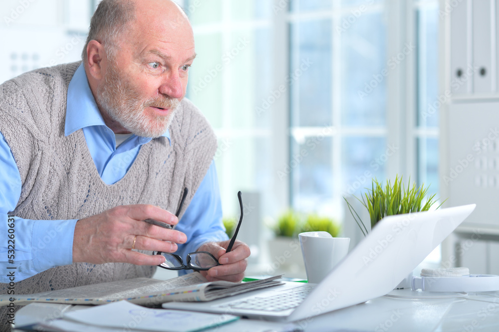 Emotional senior man reading newspaper at home Emotional senior man reading newspaper at home