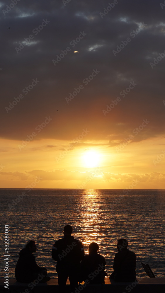 silueta de personas disfrutando de un atardecer en viña del mar con cielo iluminado por tonos anaranjados
