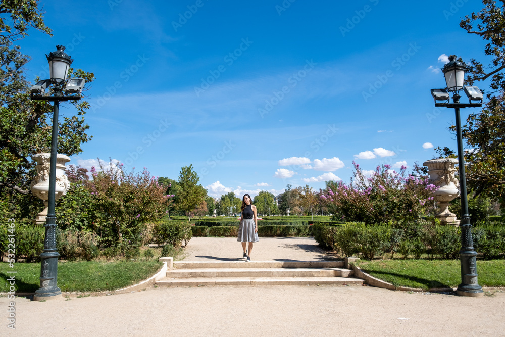Summer sunny lifestyle fashion portrait of young woman walking in a park