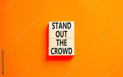 Stand out the crowd symbol. Concept words Stand out the crowd on wooden blocks on a beautiful orange table orange background. Business, stand out the crowd concept