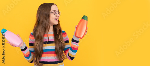 happy teen girl use shampoo bottle. child with hair conditioner. daily habits and personal care. Banner of child girl hair care, studio poster header with copy space.