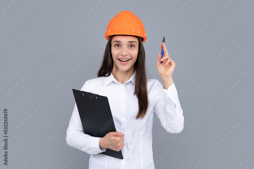 Surprised shocked excited business woman with clipboard, portrait on gray. Young woman in helmet hold laptop computer on gray background. Architect businesswoman. Surprised shocked excited business woman with clipboard, portrait on gray. Young woman in helmet hold laptop computer on gray background. Architect businesswoman.