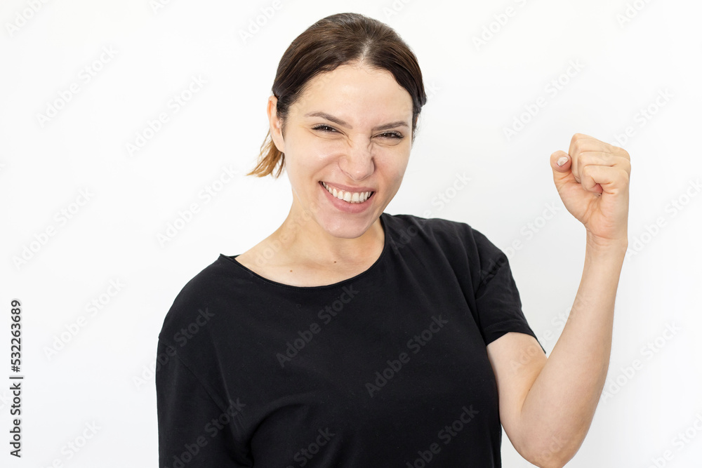 Happy woman making win gesture against white background. Portrait of excited Caucasian woman smiling, celebrating victory, looking at camera. Emotion, expression, achievement concept Happy woman making win gesture against white background. Portrait of excited Caucasian woman smiling, celebrating victory, looking at camera. Emotion, expression, achievement concept