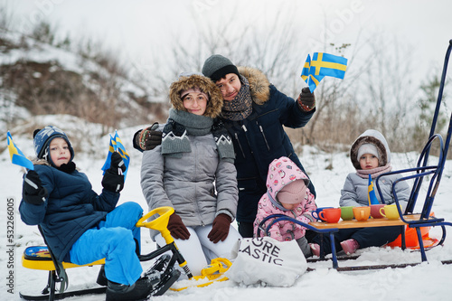 Scandinavian family with Sweden flag in winter swedish landscape.
