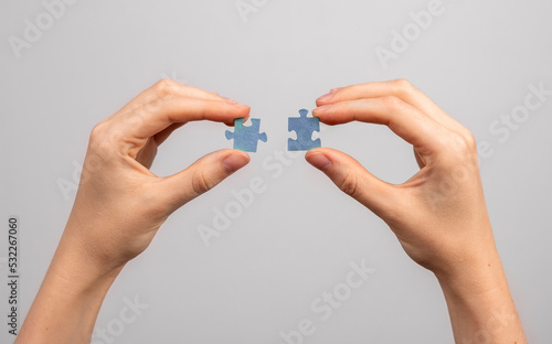 Hands connecting two jigsaw puzzle pieces closeup. Merger, business connection, assembly concept