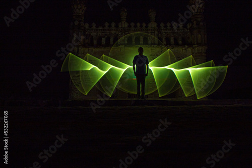 Kodanadu, Tamilnadu, India - March 14 2021 : one person standing against beautiful colorful circle light painting as the backdrop. light painting portrait, long exposure photo