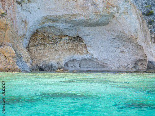 White cave on a turquoise and rocky beach in Greece