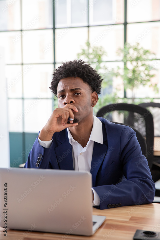 Portrait of skeptical male office worker. Serious businessman at desk looking at camera, covering mouth with hand. Business, office work concept. Portrait of skeptical male office worker. Serious businessman at desk looking at camera, covering mouth with hand. Business, office work concept.