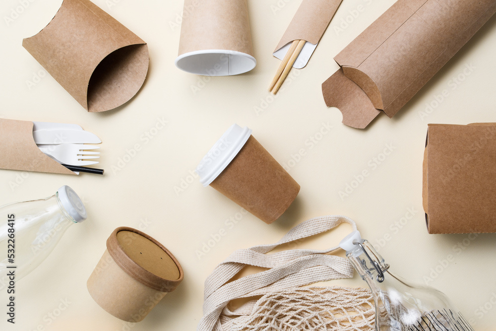 Naklejka premium Eco-friendly packaging and utensils around a paper cup for coffee on a yellow background. The concept of ecology and zero waste.