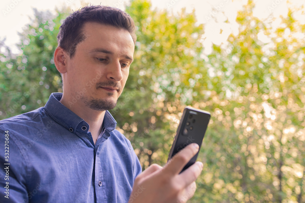Young man using his mobile phone outdoors. Handsome man using smartphone at the park. Young man using his mobile phone outdoors. Handsome man using smartphone at the park.