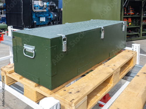 Steel box on pallet. Case for storage and transportation of equipment. Heavy equipment box. Closed green box in open air. Case for reliable transportation of industrial equipment.
