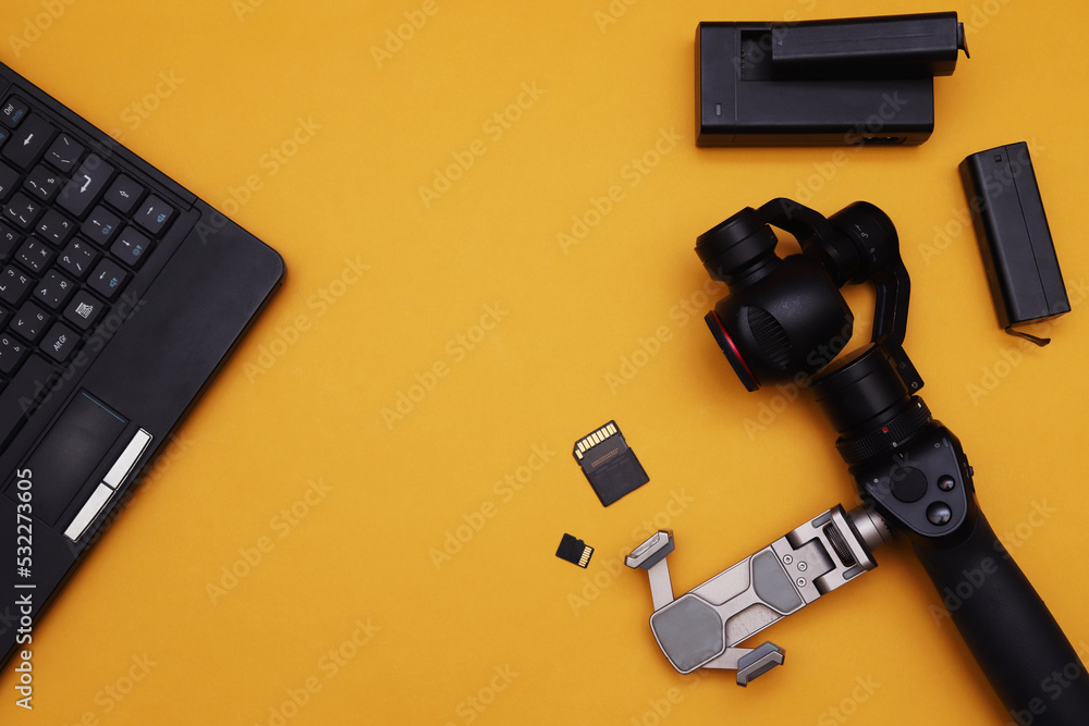 Fototapeta premium action camera with a miniature mechanical stabilizer and a laptop on an orange background.