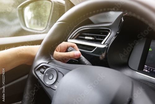 female hand turns on the turn signals on the car