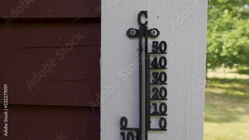 Old thermometer outside on house facade showing thirty plus degree celcius  photo