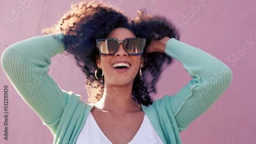 Hair care, fashion sunglasses and black woman happy in summer, smile for summer curls and excited about luxury glasses against pink city wall. Portrait of comic girl with curly hair on street photo