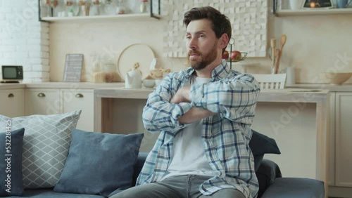 Tired middle-aged bearded man reacting violently to news on social networks, watching ads and angrily throwing smartphone in living room at home.