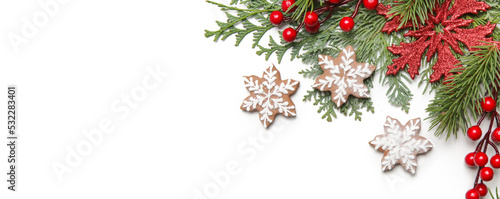 Christmas decoration. Christmas tree branches, red berries and snow flake shaped cookies on white background.
