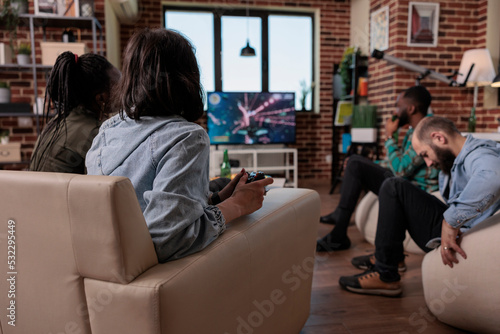 Group of friends having fun with shooter video games on tv, using console to play on television. Playing shooting game at social gathering with people, enjoying leisure activity and gaming.
