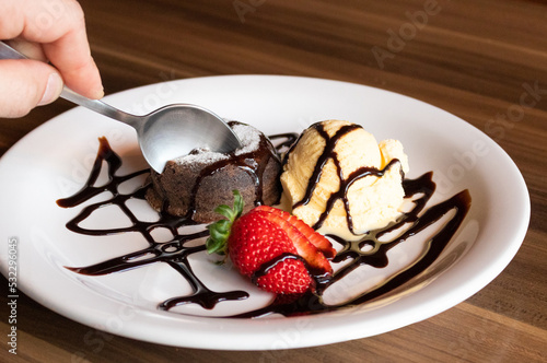Person serving petit gateau with cream ice cream