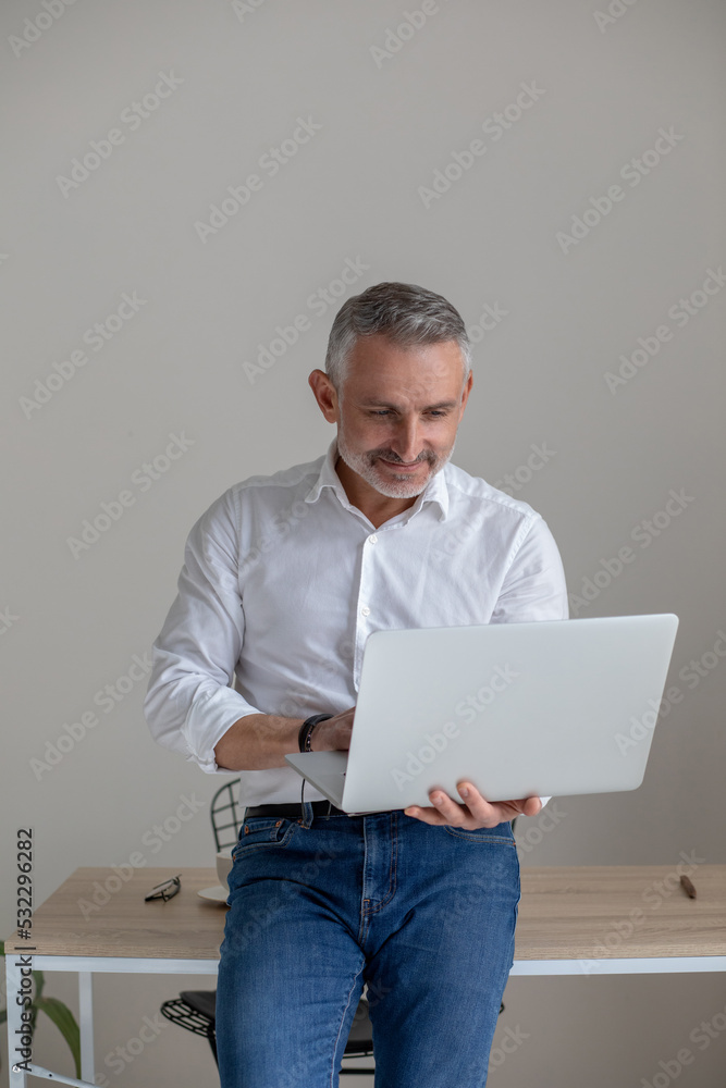 Gray-haired mid aged businessman with a laptop in hands Gray-haired mid aged businessman with a laptop in hands