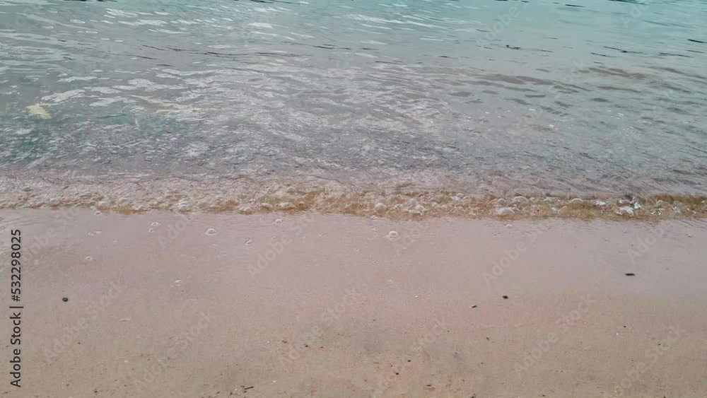 Sea waves lapping against shore. Sandy beach and blue water. Summer holiday concept, natural background. Sea waves lapping against shore. Sandy beach and blue water. Summer holiday concept, natural background.