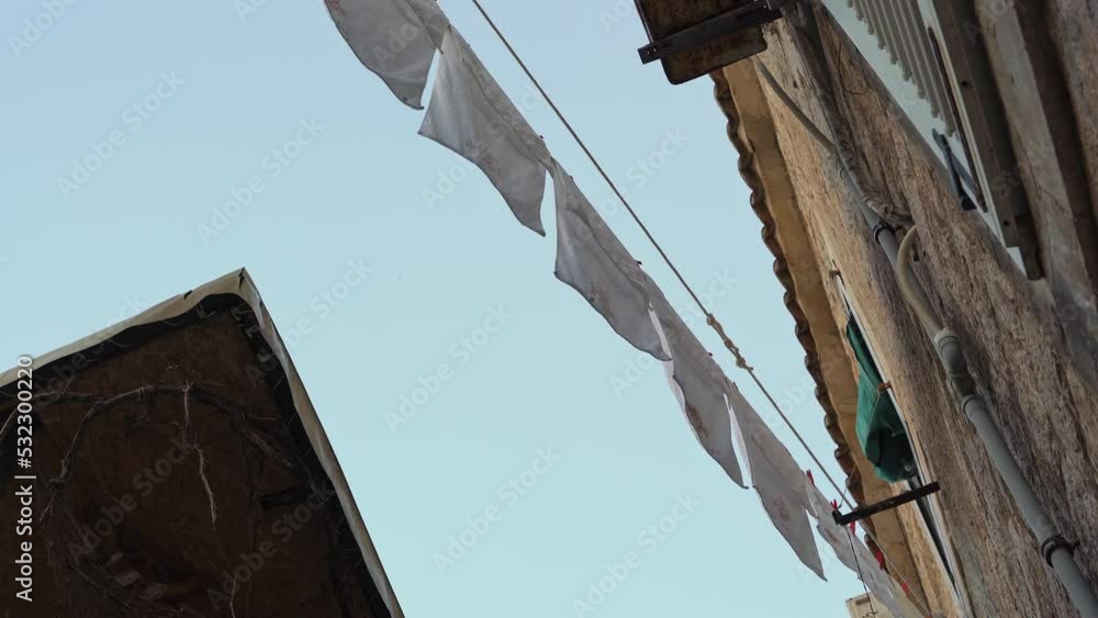 white laundry is drying on a rope against the background of old brick buildings and blue sky. clean linen dries in the sun. white laundry is drying on a rope against the background of old brick buildings and blue sky. clean linen dries in the sun.