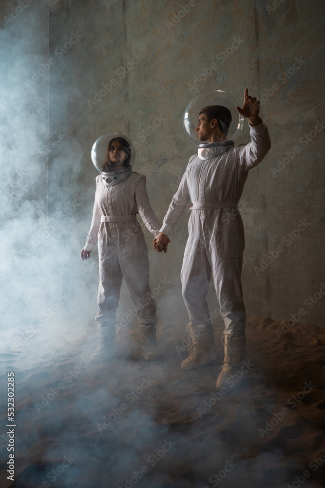 Astronauts in an empty colony on a deserted planet, a man and a woman in white futuristic spacesuits explore the area