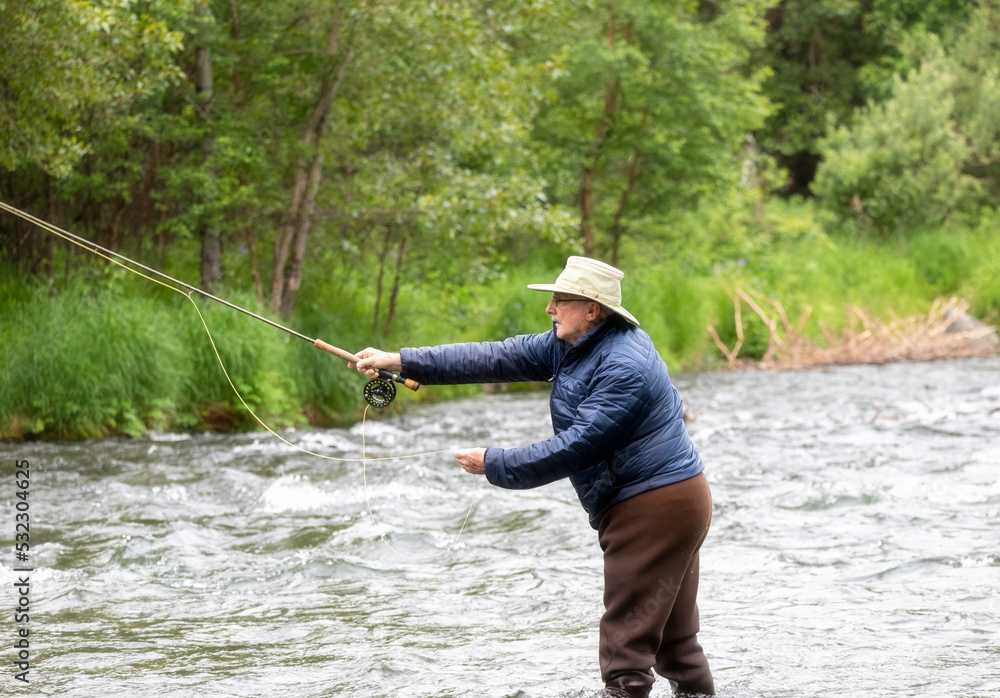 An older gentleman tries his luck at fly fishing for salmon.  Russian River.  Cooper Landing, Alaska.