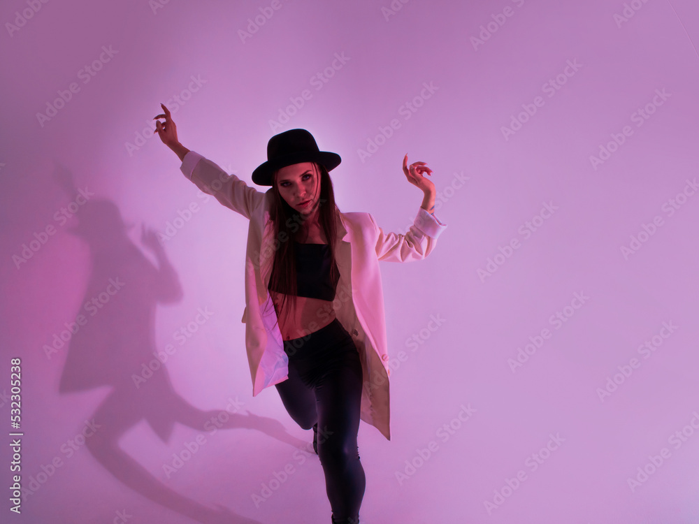 Stylish young woman in a black hat and jacket. posing in the studio with pink light on the background Stylish young woman in a black hat and jacket. posing in the studio with pink light on the background