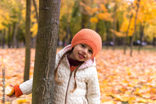 One happy funny child kid Girl orande Hat walking in park forest enjoying autumn fall nature weather. siblings Kid Collect falling leaves in baskets, playing hiding tree play hide and seek together photo