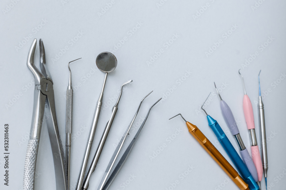 Metal tools of the dentist on a white background. Aesthetics of dentistry. Forceps, tweezers, mirror, curettes and scalers on a white background