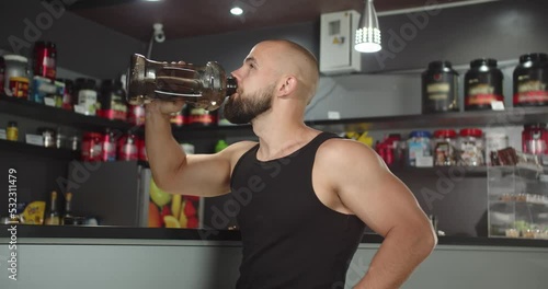 A man replenishes the water balance in his body during training in the gym photo