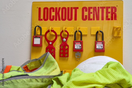 lockout/tagout station with tagout and locks attached surrounded by safety vest and white hard hat photo