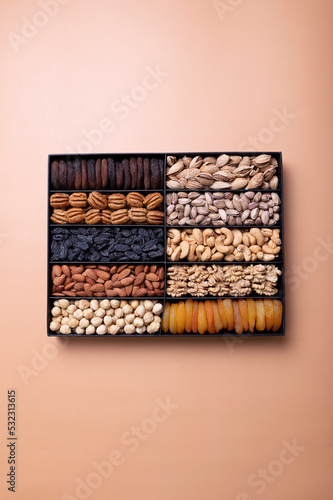 Hazelnuts, almonds, raisins, dried apricots, peanuts, cashews, pistachios in a box.