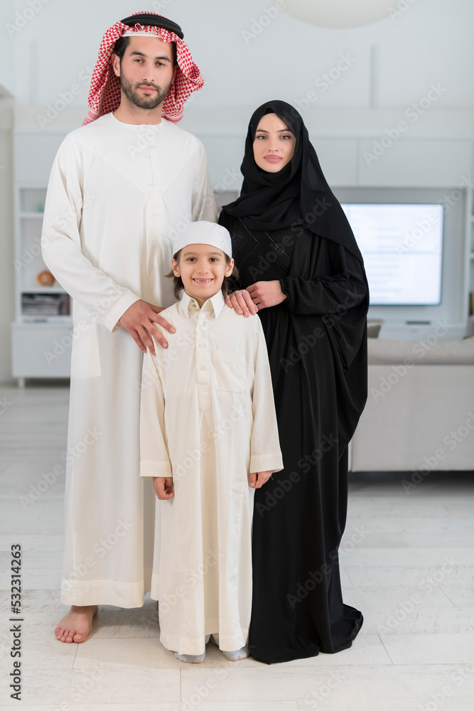 Portrait of a young happy Arabian Muslim family couple with a son in traditional clothes spending time together