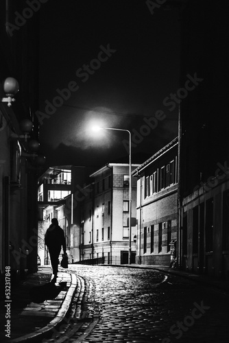 Lone silhouette walks on a street at night