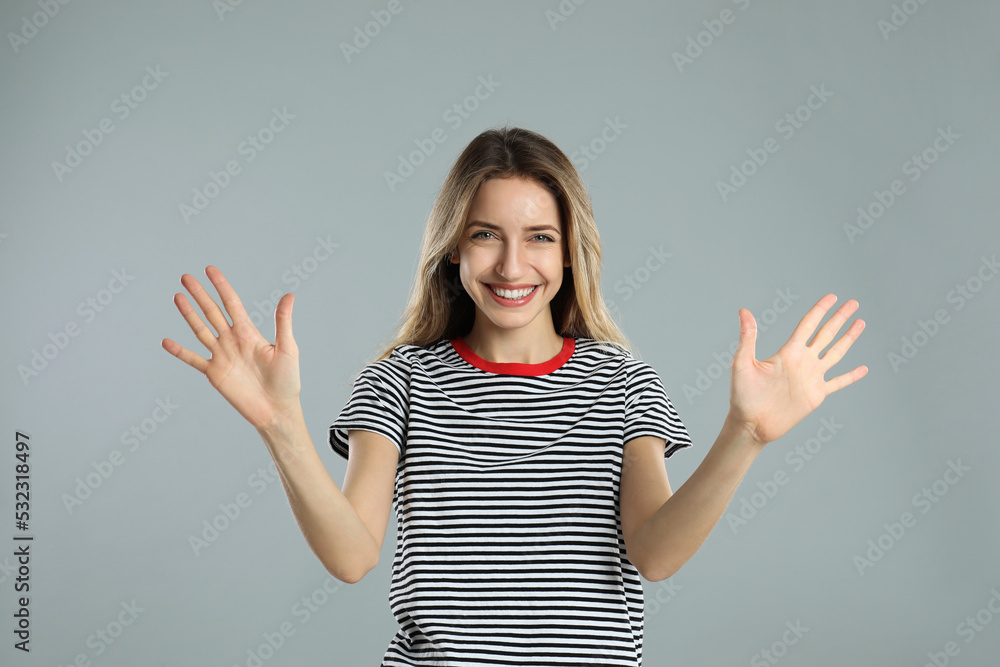 Woman showing number ten with her hands on light grey background Woman showing number ten with her hands on light grey background