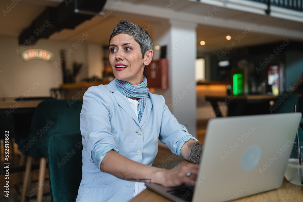 One woman mature adult senior female work on laptop at cafe One woman mature adult senior female work on laptop at cafe