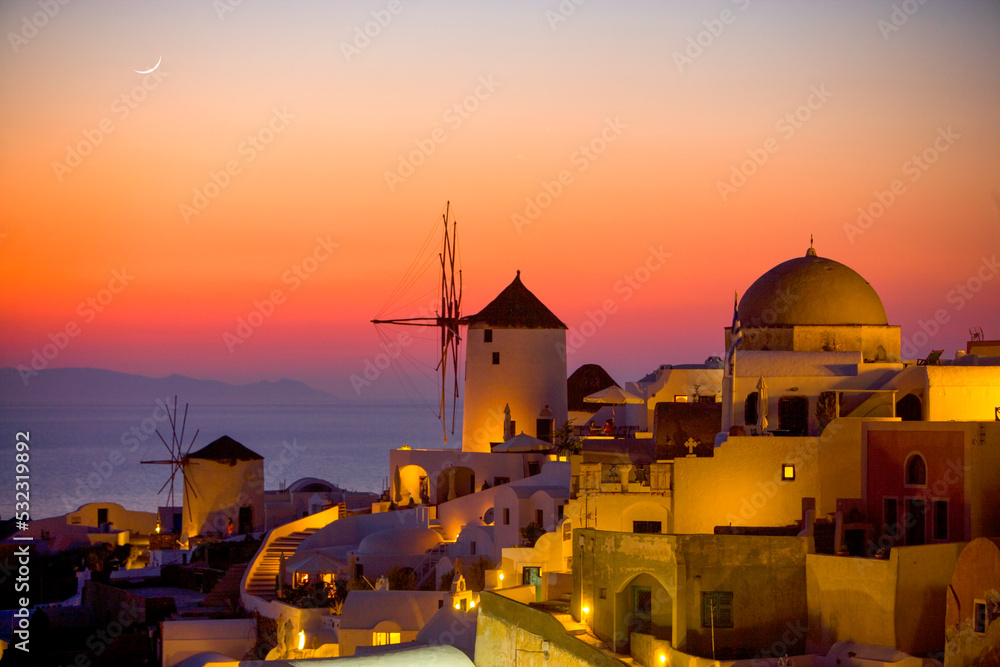 Greece, Santorini, Oia. Sunset on ocean and town buildings.