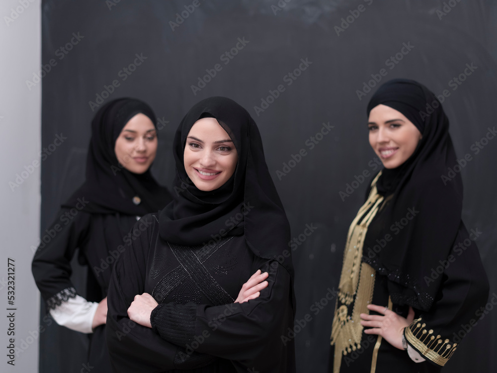 Group portrait of beautiful Muslim women in a fashionable dress with hijab isolated on black background Group portrait of beautiful Muslim women in a fashionable dress with hijab isolated on black background